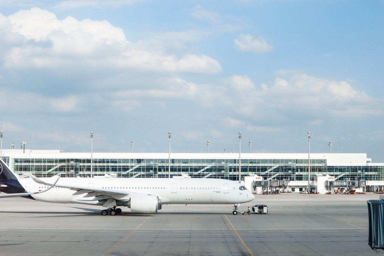 Un avion long-courrier au poste de stationnement devant une jetée d'embarquement vitrée