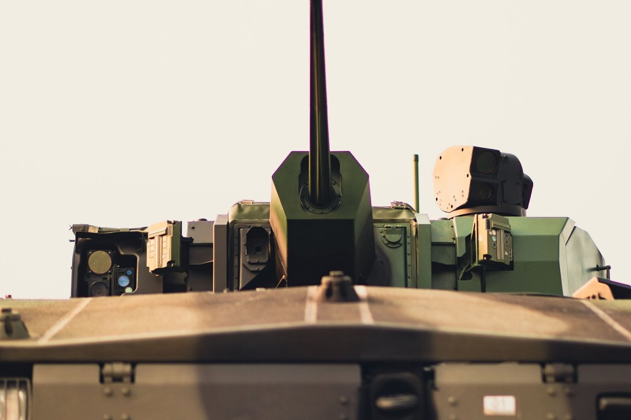La tourelle et le canon d'un véhicule blindé de combat, vus de face sur un ciel clair