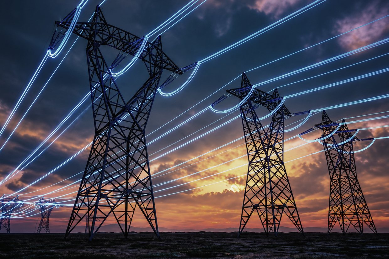 Trois pylônes de transport d'électricité au crépuscule, les conducteurs filant vers l'horizon