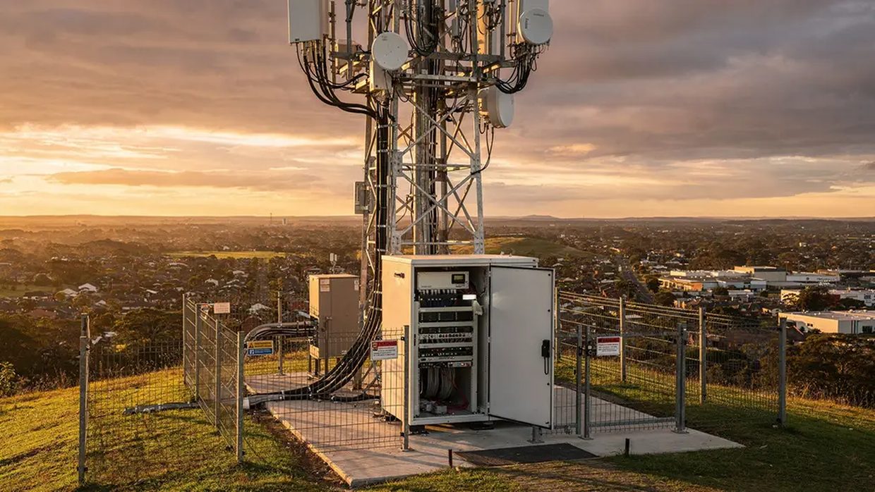 Un site d'antenne en fin de journée, l'armoire technique ouverte au pied du pylône